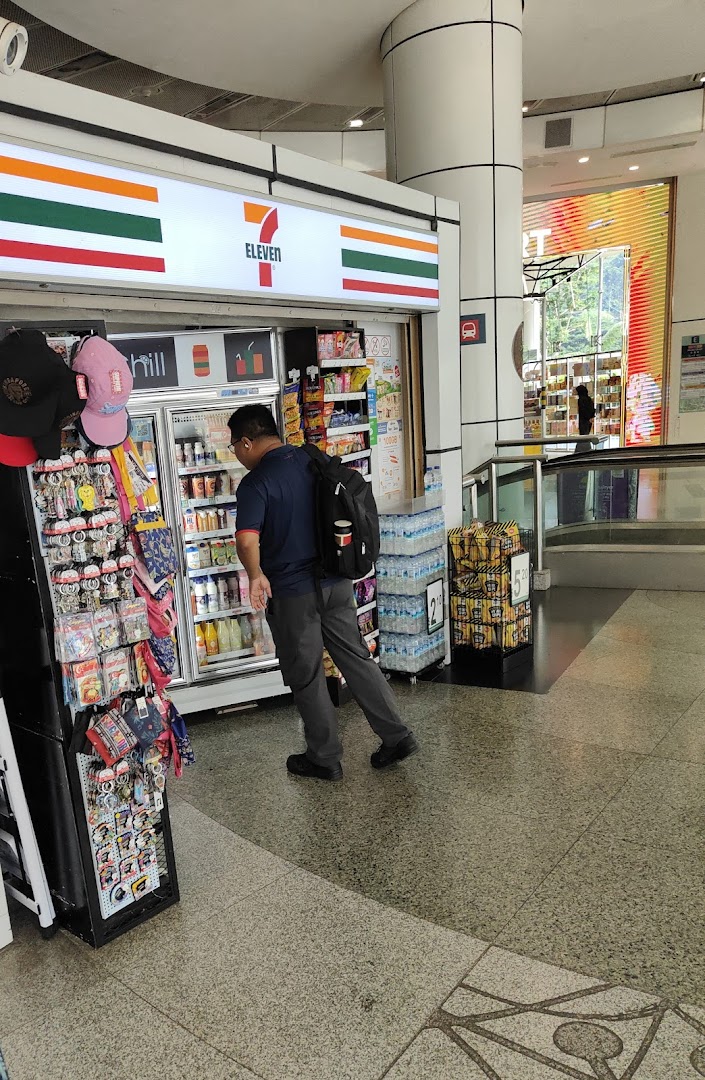 A customer browses beverages inside a well-stocked 7-Eleven convenience store, featuring its iconic signage.