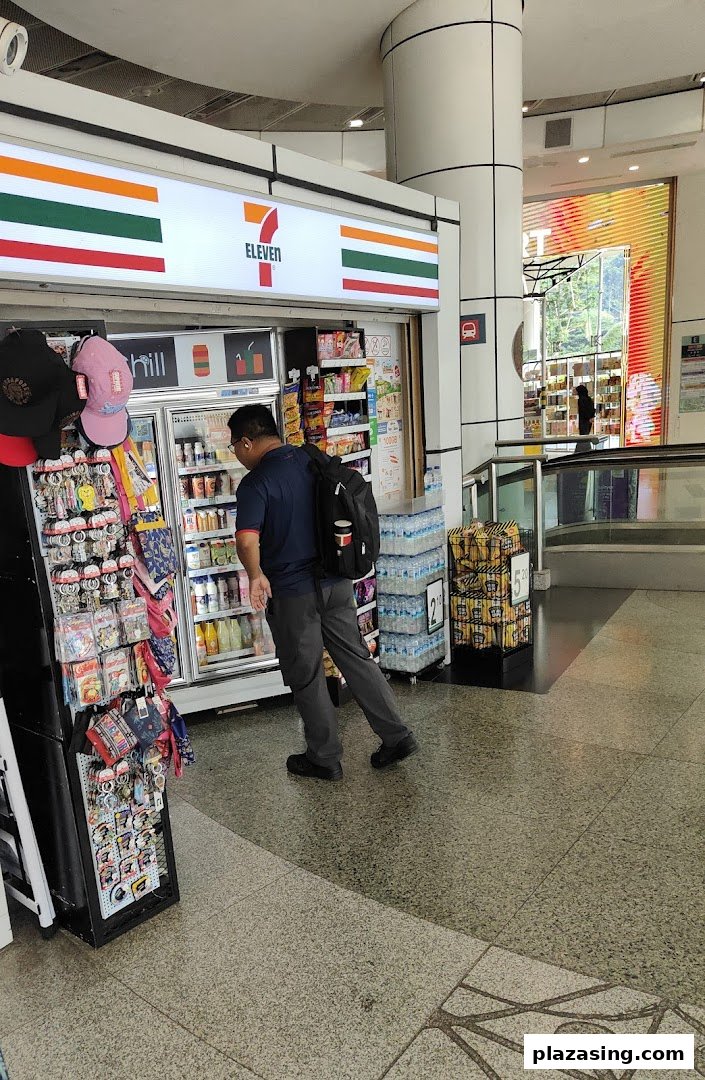 A customer browses beverages inside a well-stocked 7-Eleven convenience store, featuring its iconic signage.