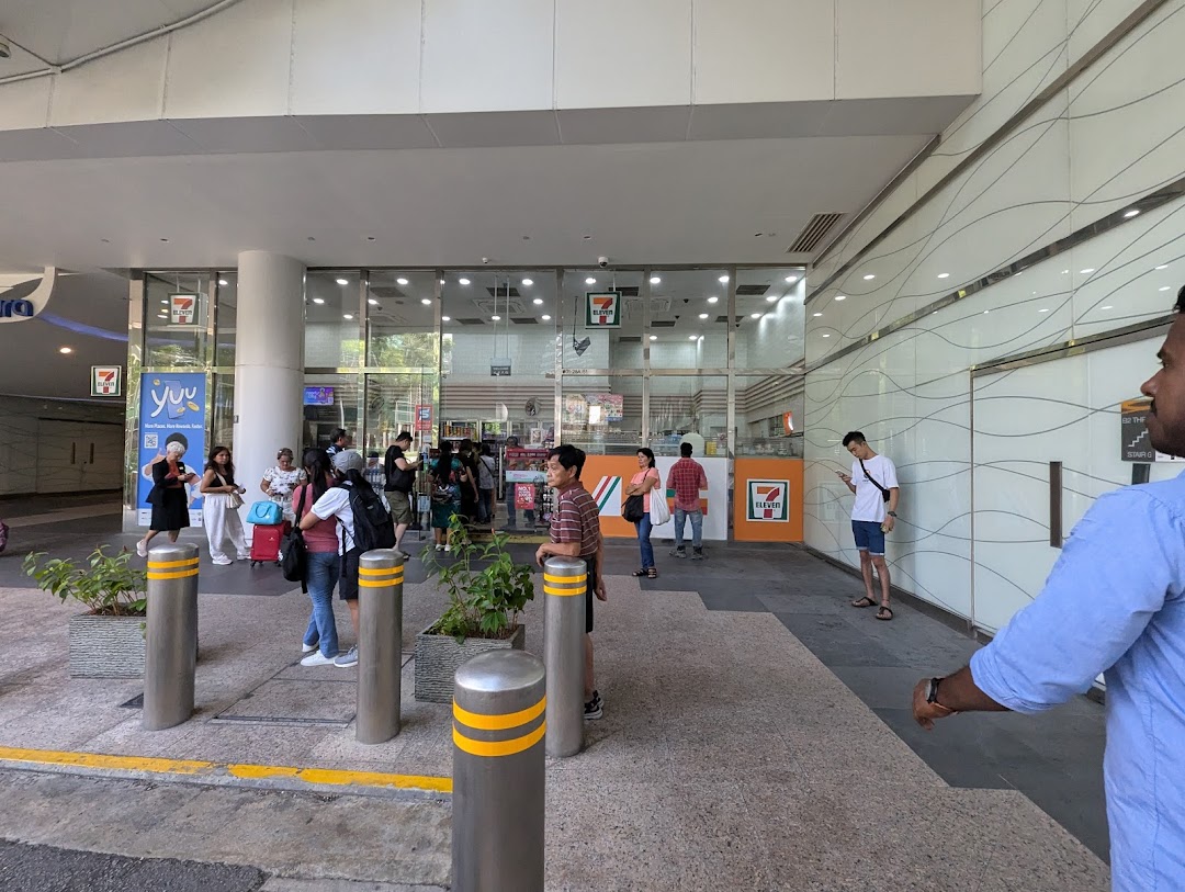 Exterior view of 7-Eleven Plaza Singapura with customers entering and exiting the convenience store.
