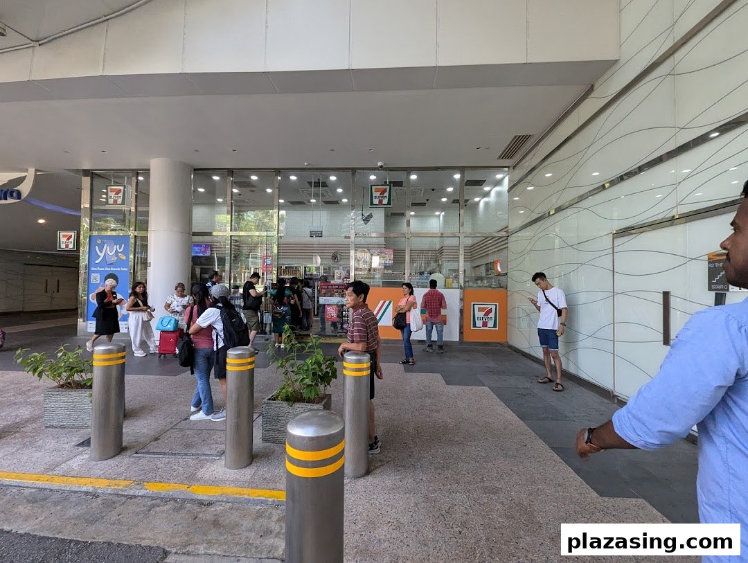 Exterior view of 7-Eleven Plaza Singapura with customers entering and exiting the convenience store.