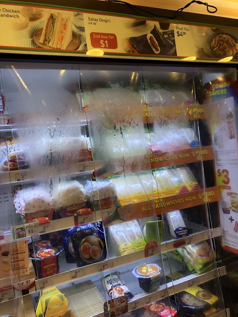 A refrigerated display case at 7-Eleven showcasing a variety of ready-to-eat meals, sandwiches, and snacks.