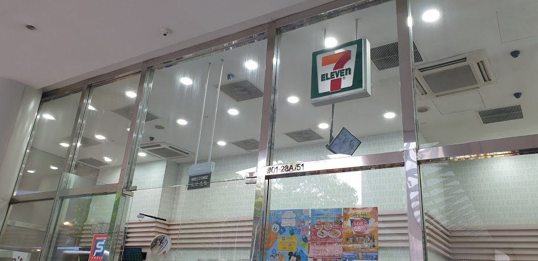The glass entrance of 7-Eleven Plaza Singapura, featuring its iconic logo and promotional posters.