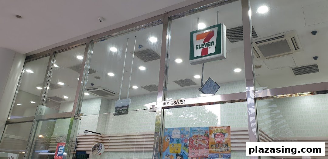 The glass entrance of 7-Eleven Plaza Singapura, featuring its iconic logo and promotional posters.