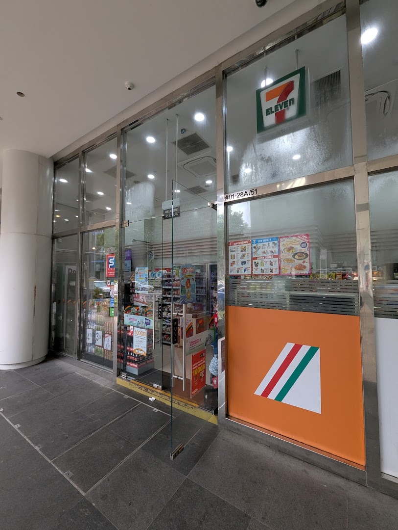 The exterior of 7-Eleven Plaza Singapura, showcasing its glass entrance and visible interior.
