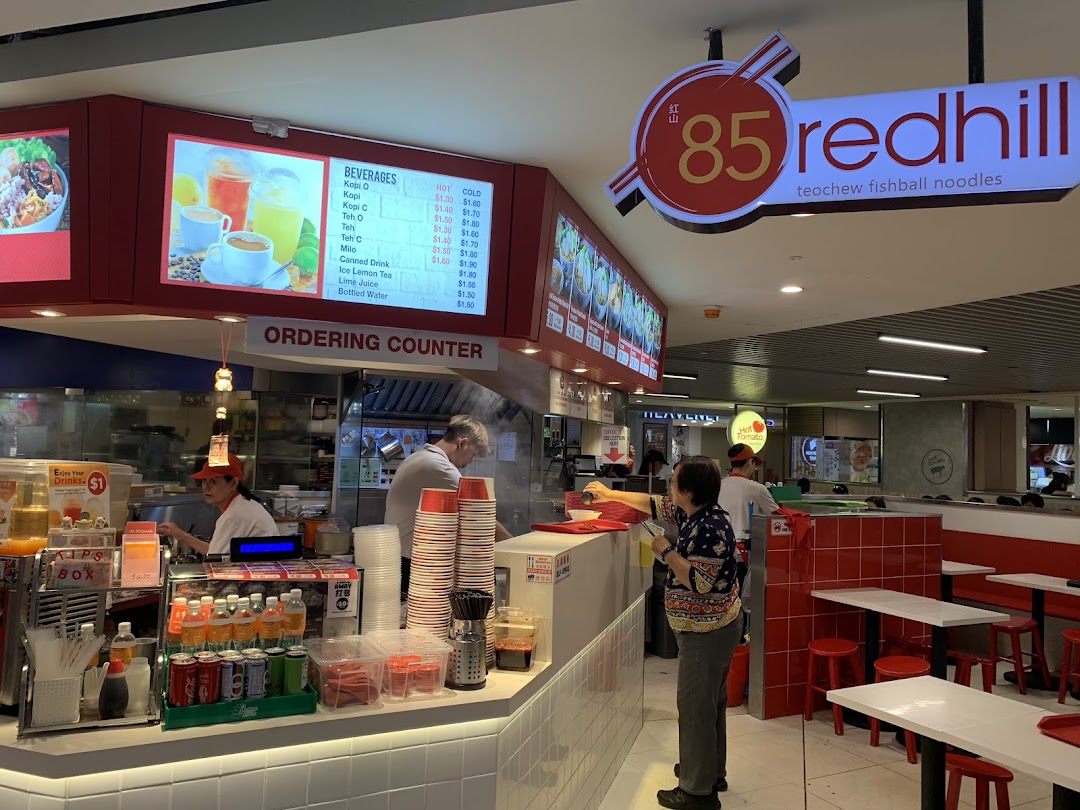 A vibrant interior shot of 85 Redhill Teochew Fishball Noodle, featuring the ordering counter and beverage menu.