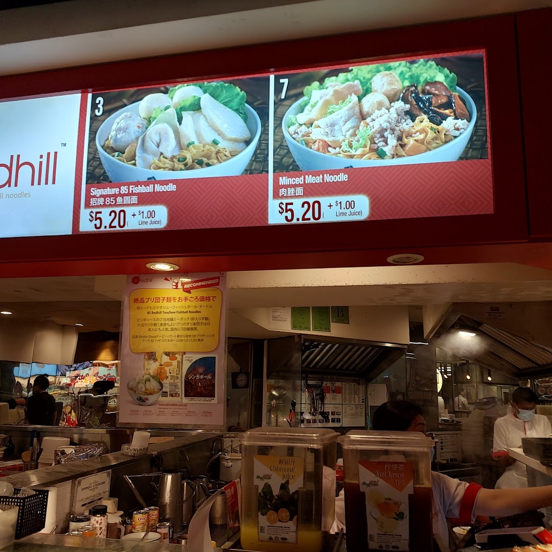 A digital menu board displays Signature Fishball Noodle and Minced Meat Noodle prices at a food stall.