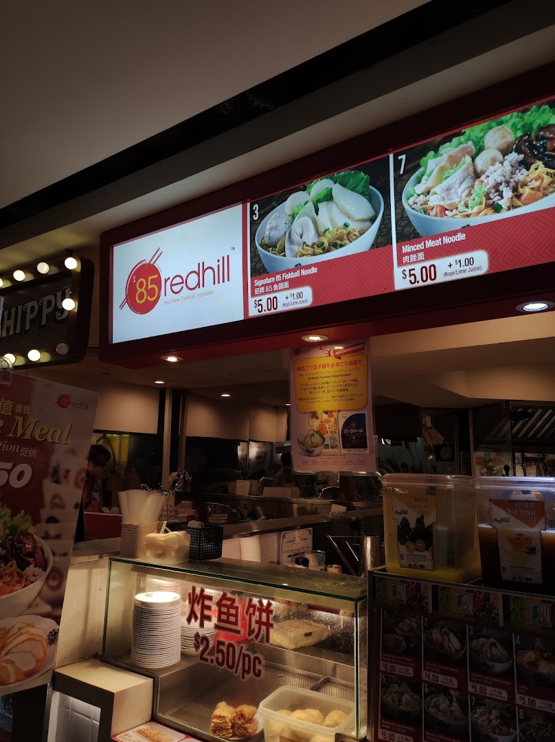 A brightly lit menu board showcasing signature noodle dishes and prices at 85 Redhill Teochew Fishball Noodle.