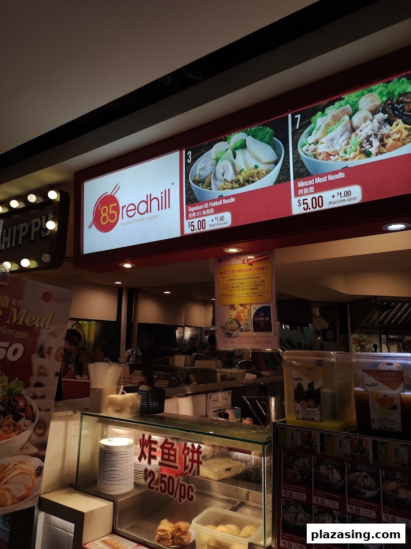 A brightly lit menu board showcasing signature noodle dishes and prices at 85 Redhill Teochew Fishball Noodle.