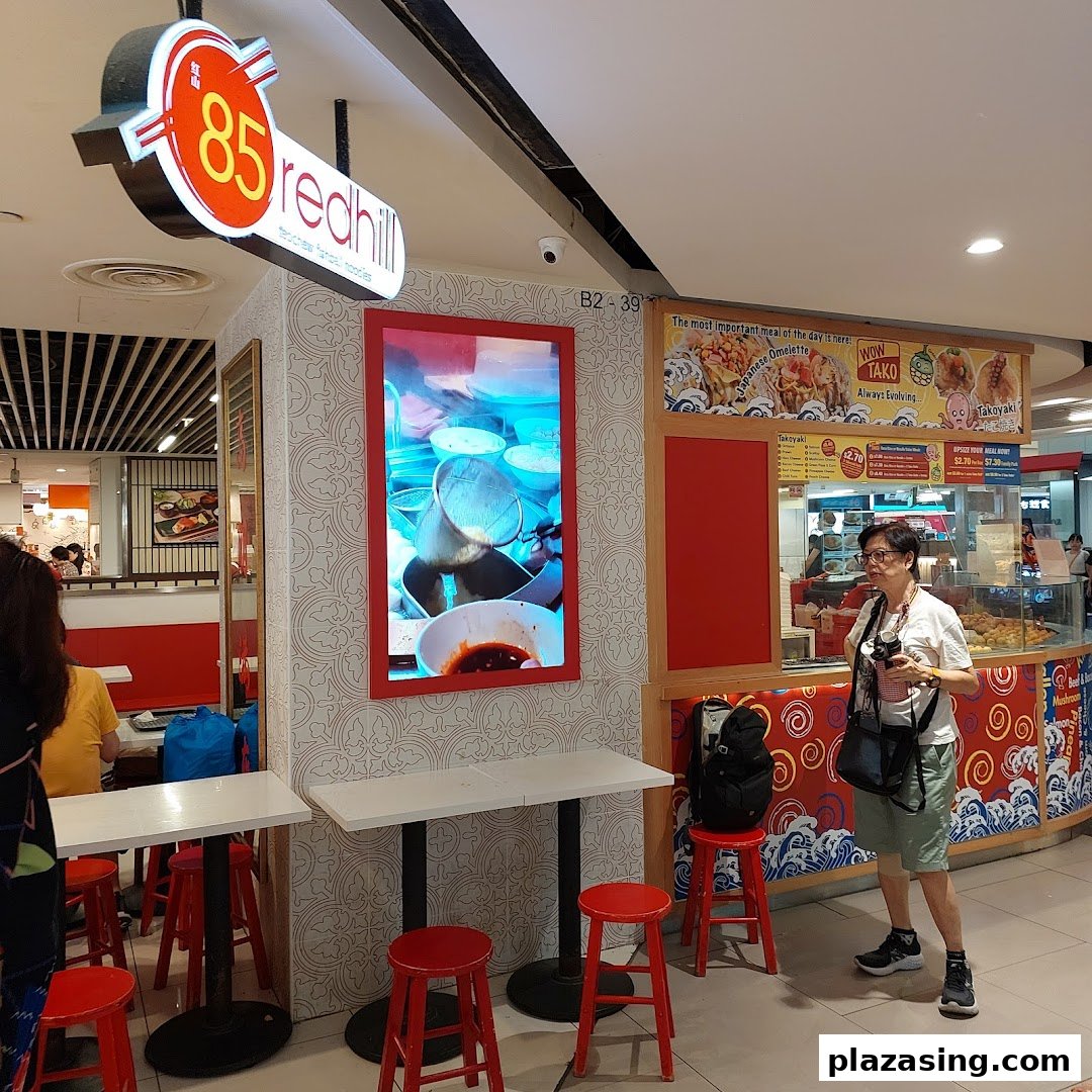 The shop front of 85 Redhill Teochew Fishball Noodle, featuring its signage and a digital display.
