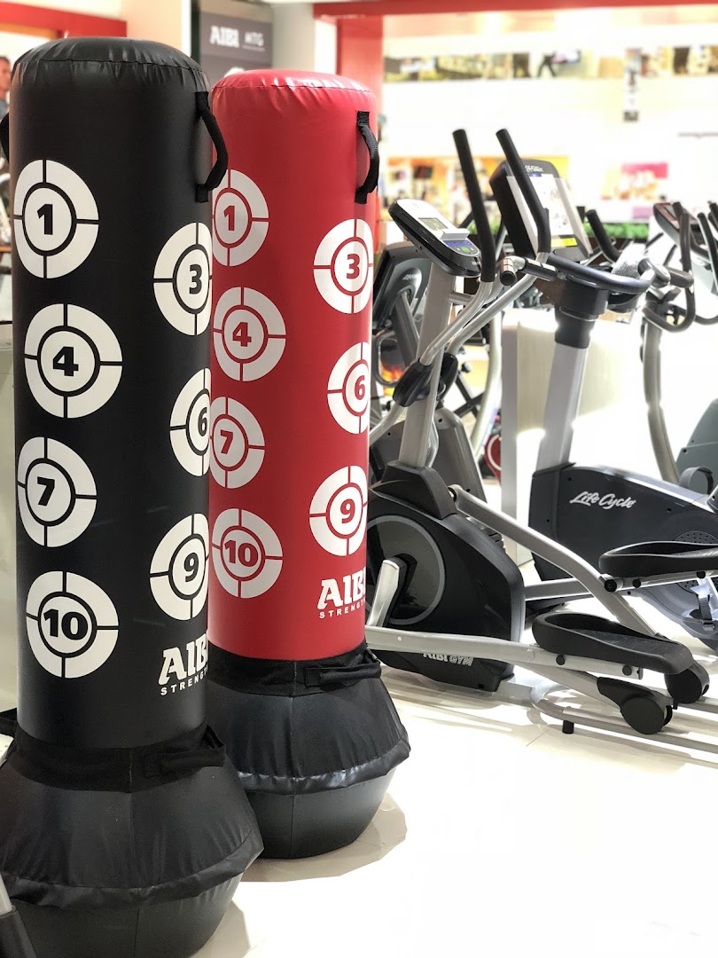 Two punching bags and various fitness machines are displayed inside the Aibi sports and fitness store.