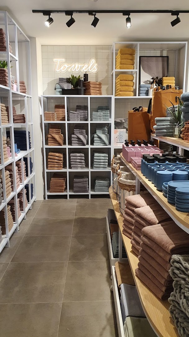 Interior view of AKEMI, showcasing neatly folded towels and bath accessories on modern display shelves.