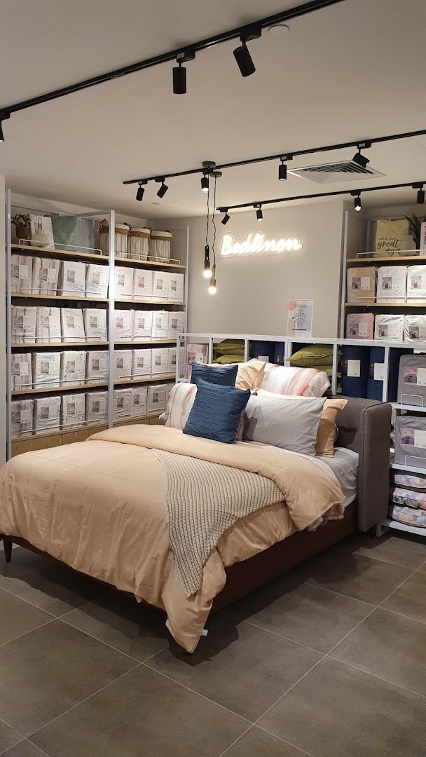 An inviting bed display showcasing various bedding sets and home textiles in a retail store.