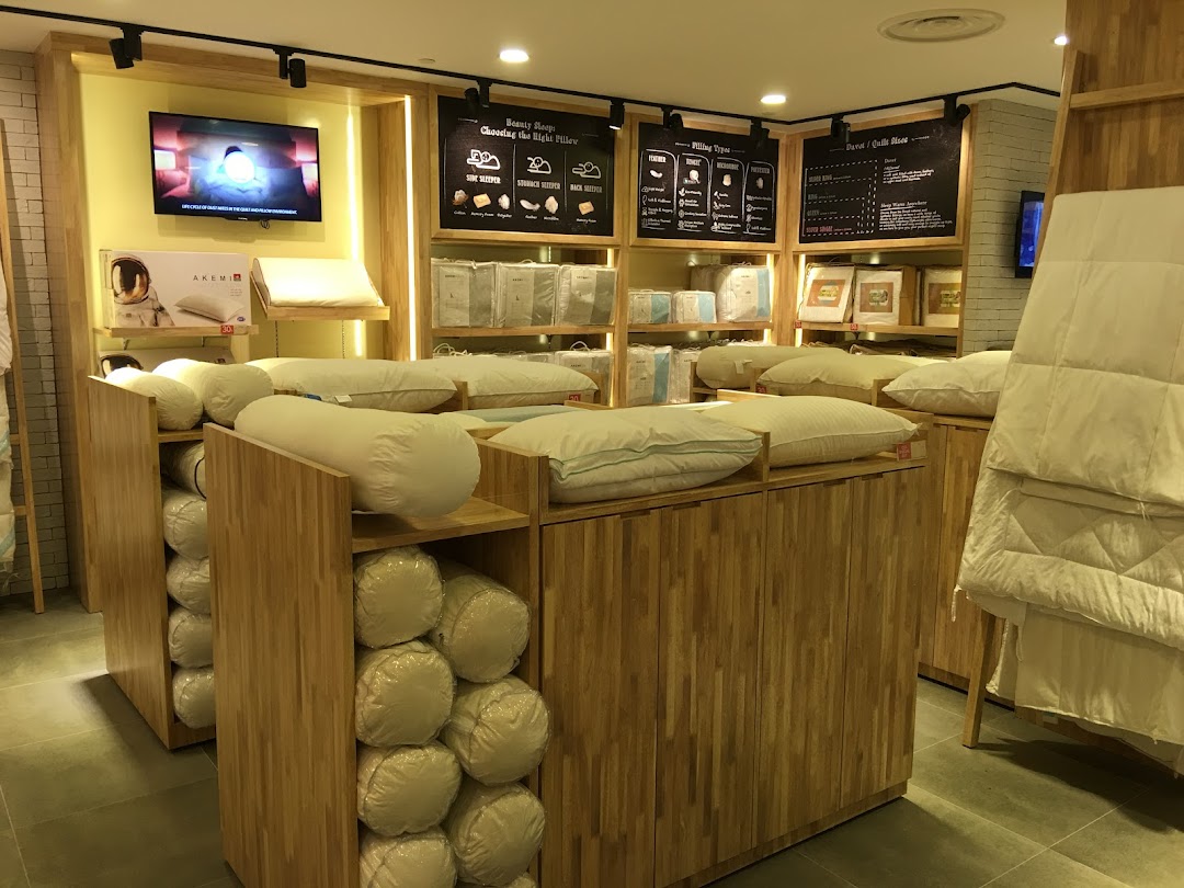 Interior view of AKEMI bedding store showcasing pillows, bolsters, and duvets on wooden displays.