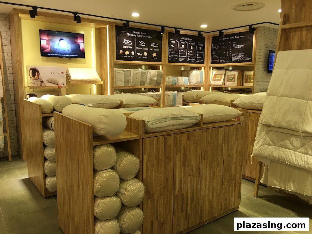 Interior view of AKEMI bedding store showcasing pillows, bolsters, and duvets on wooden displays.