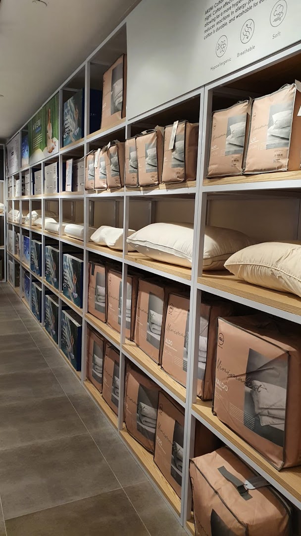 Shelves filled with packaged bedding, pillows, and home linen products inside the AKEMI store.