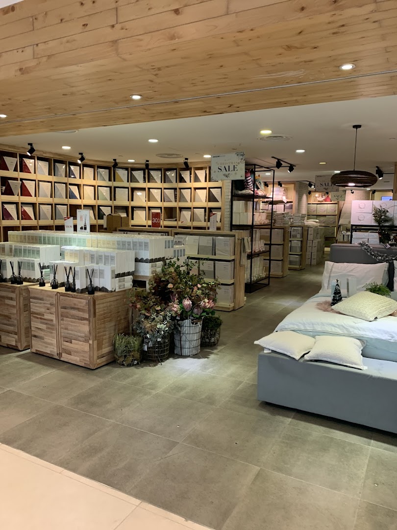 Interior view of AKEMI, showcasing bedding displays, diffusers, and home decor items in a retail setting.