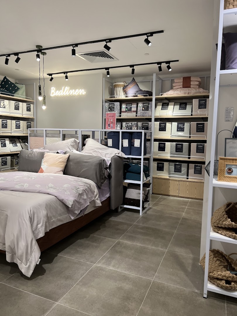 Interior view of AKEMI, showcasing bed linen, pillows, and a display bed setup with shelves of products.