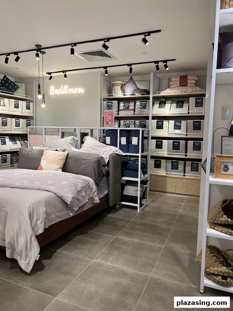 Interior view of AKEMI, showcasing bed linen, pillows, and a display bed setup with shelves of products.
