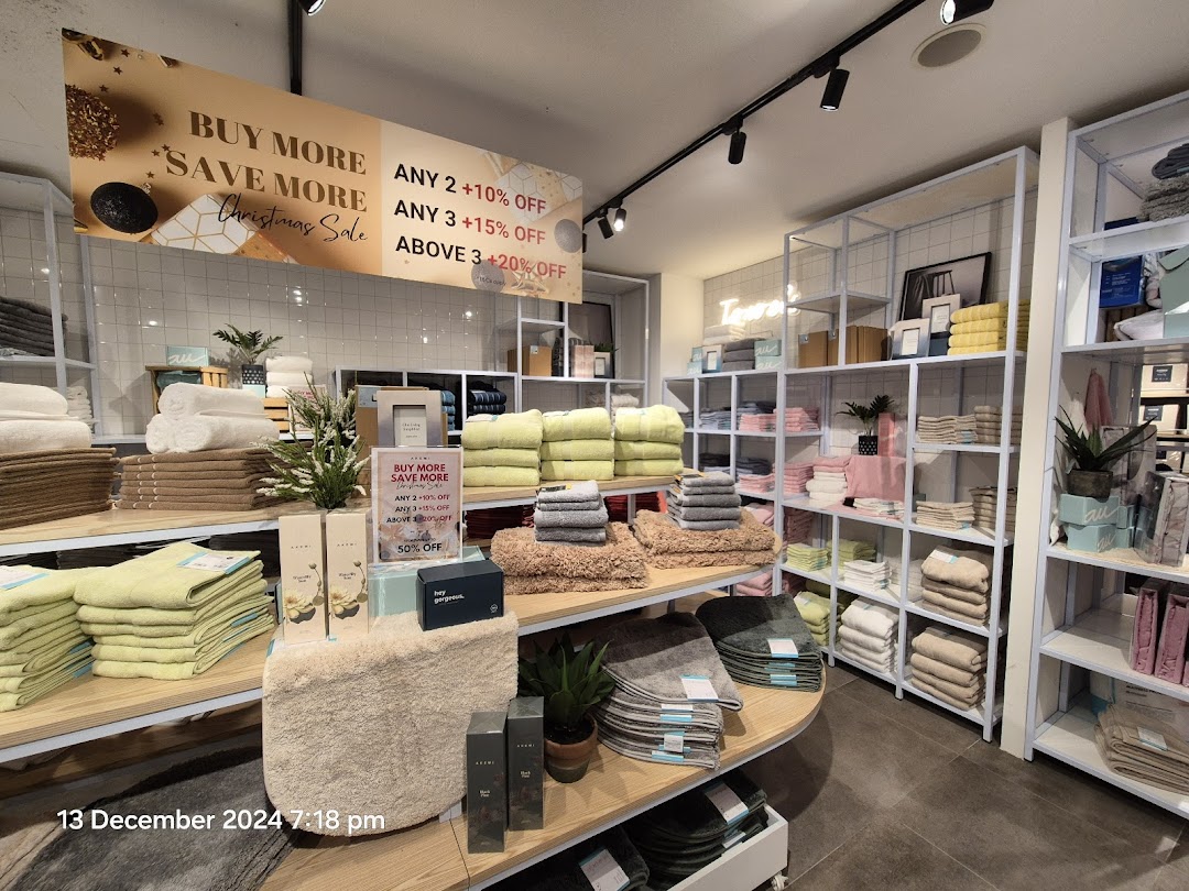 Interior view of AKEMI store showcasing neatly folded towels and home textiles with a Christmas sale banner.
