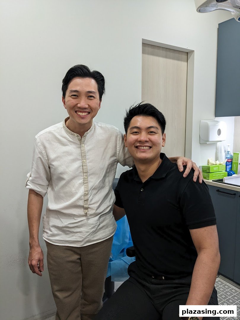 Two smiling men, likely a clinic staff and patient, in a modern clinic setting.