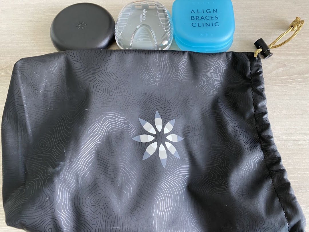 A black drawstring bag with dental aligner cases, including one labeled 'Align Braces Clinic'.