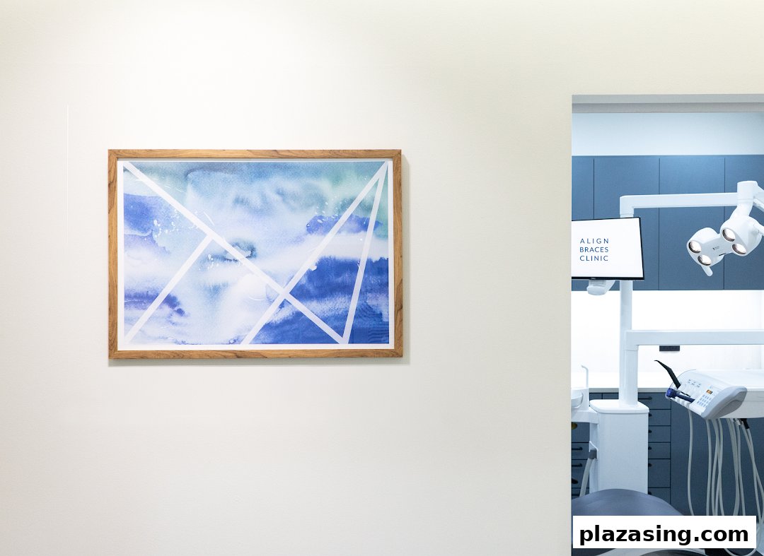 A modern dental clinic interior featuring a treatment chair, equipment, and wall art.