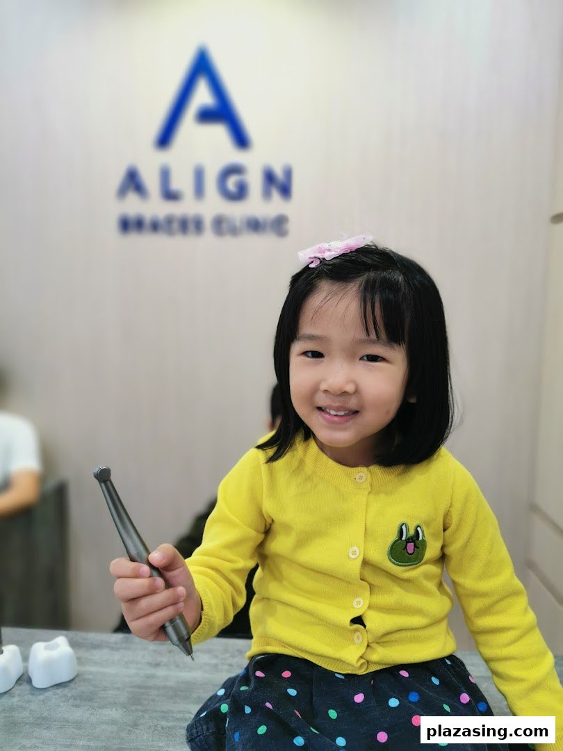 A smiling child holds a dental tool inside Align Braces Clinic.