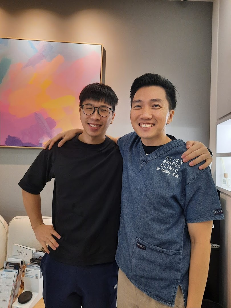 Two smiling men, one a doctor from Align Braces Clinic, stand together in a modern clinic interior.
