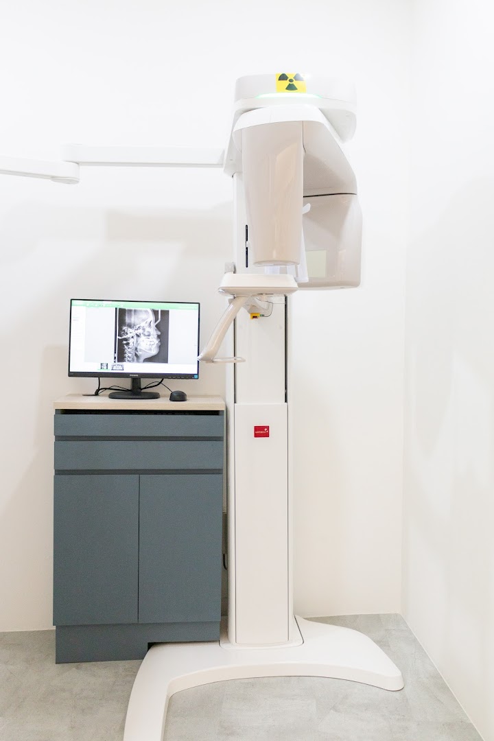 An advanced dental X-ray machine and monitor displaying a skull X-ray in a modern clinic.