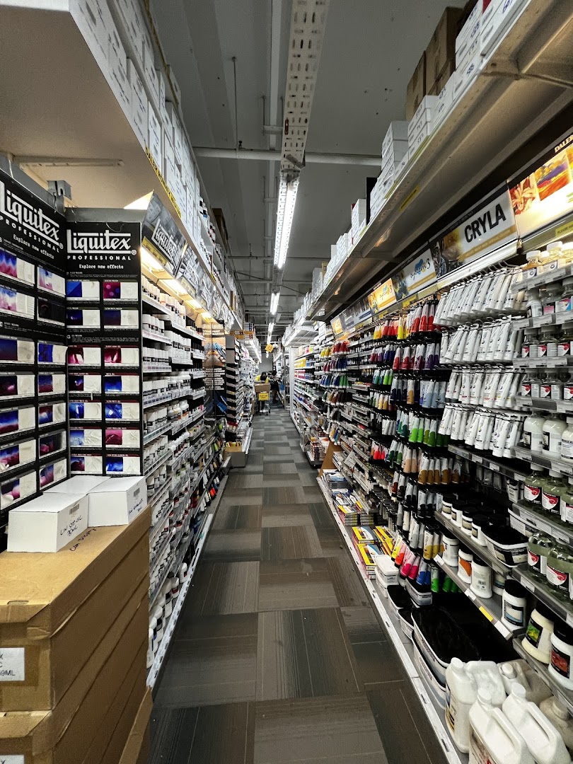 A long aisle inside Art Friend, showcasing a wide array of art supplies like paints and mediums on well-stocked shelves.