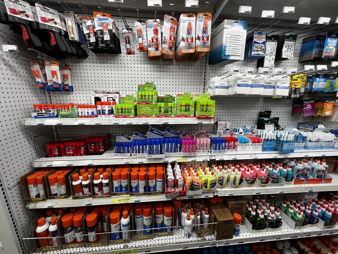 Shelves at Art Friend displaying a wide variety of glues, adhesives, and craft supplies.