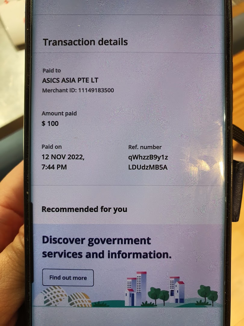 A phone screen displaying transaction details for a $100 payment made to ASICS ASIA PTE LT.