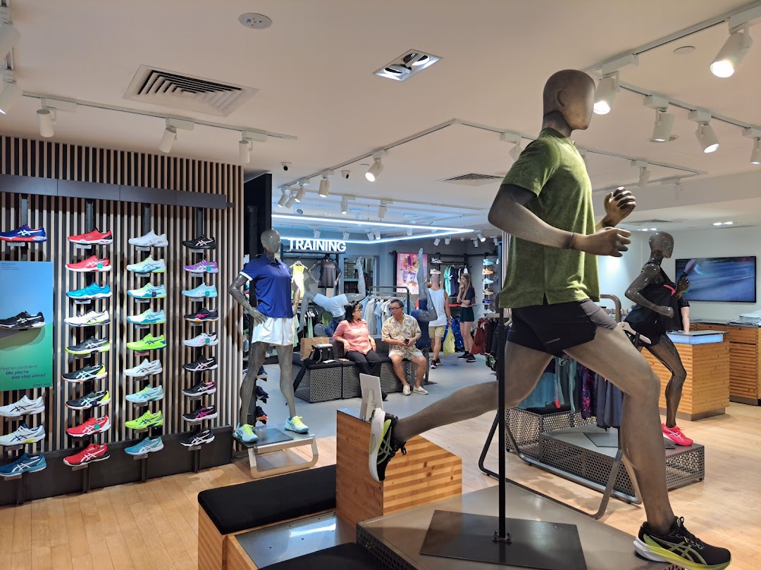 Interior view of an ASICS store showcasing running shoes on display and athletic mannequins.