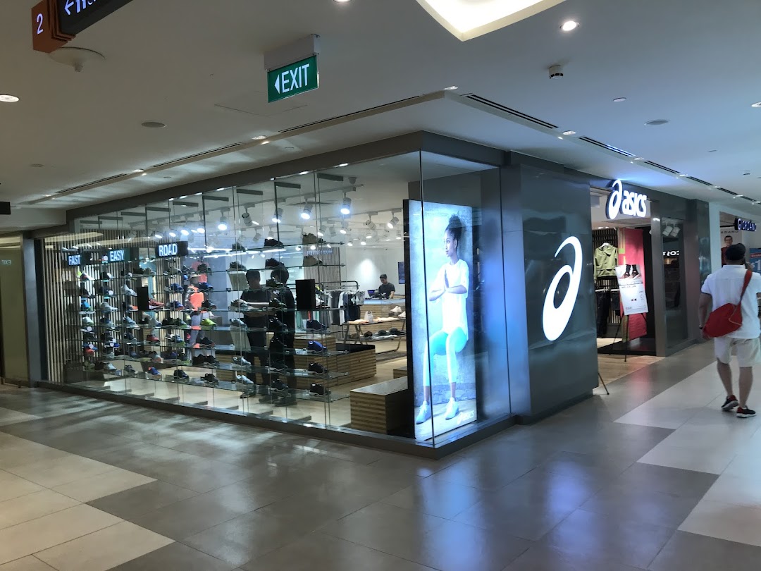 The ASICS store entrance features a large logo, illuminated display, and a wide selection of athletic footwear.