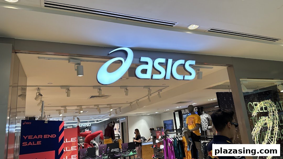 The brightly lit entrance of an ASICS retail store, showcasing its prominent logo and inviting interior.