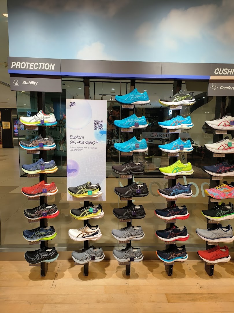 A vibrant display of ASICS running shoes showcasing various models and colors in a retail store.