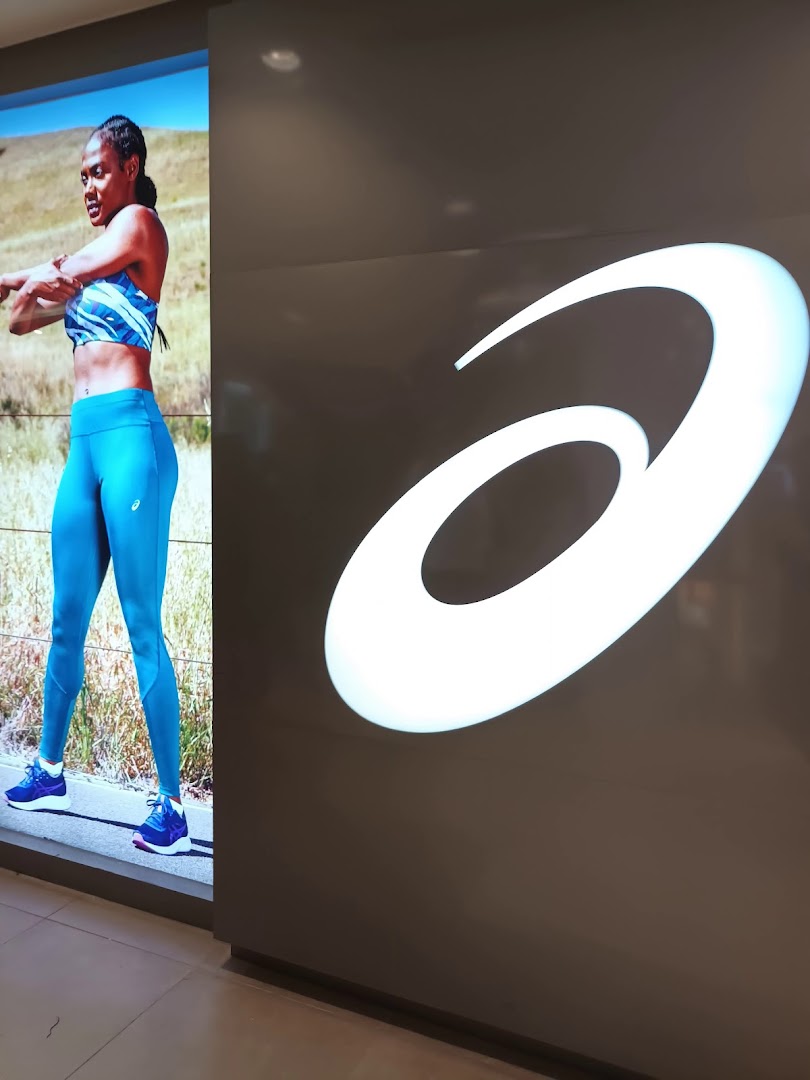A large illuminated ASICS logo next to a digital display featuring an athlete in activewear.