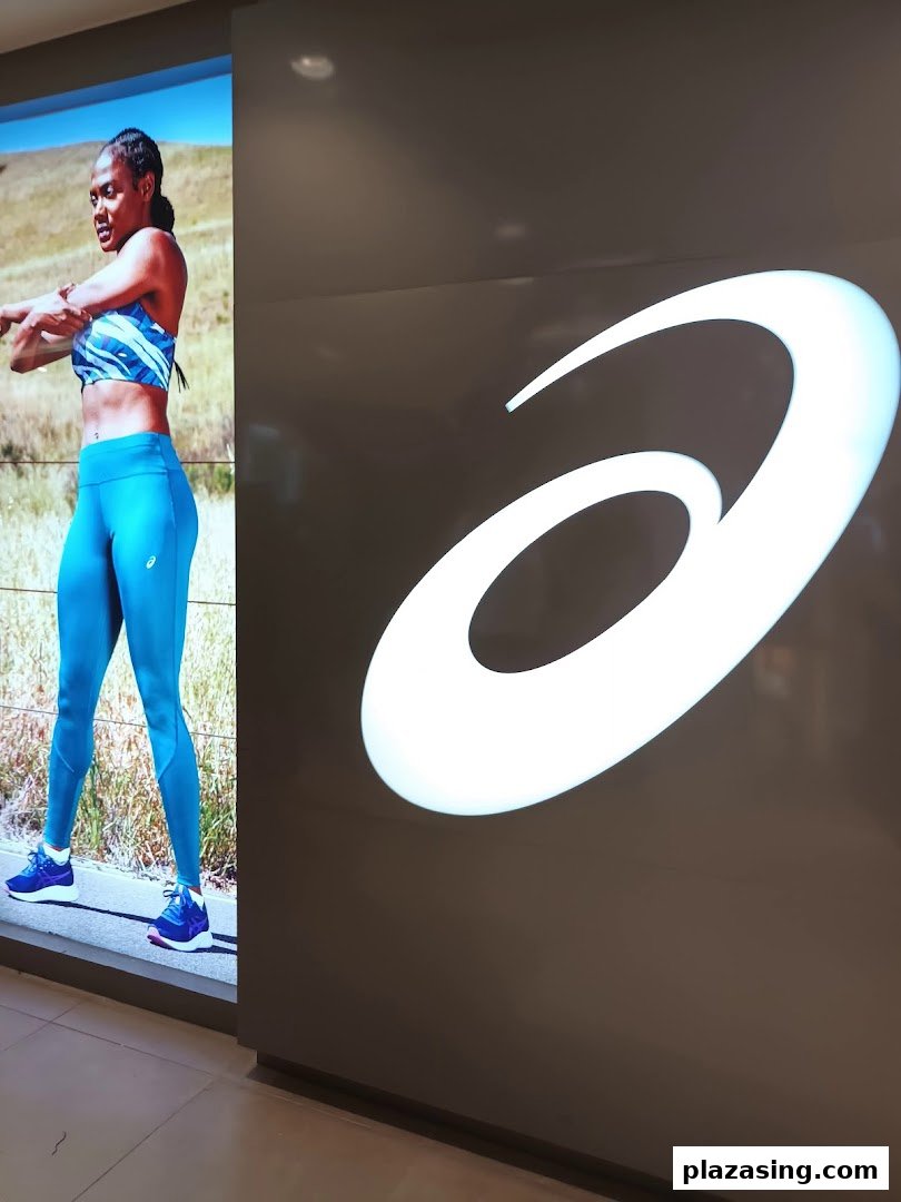 A large illuminated ASICS logo next to a digital display featuring an athlete in activewear.