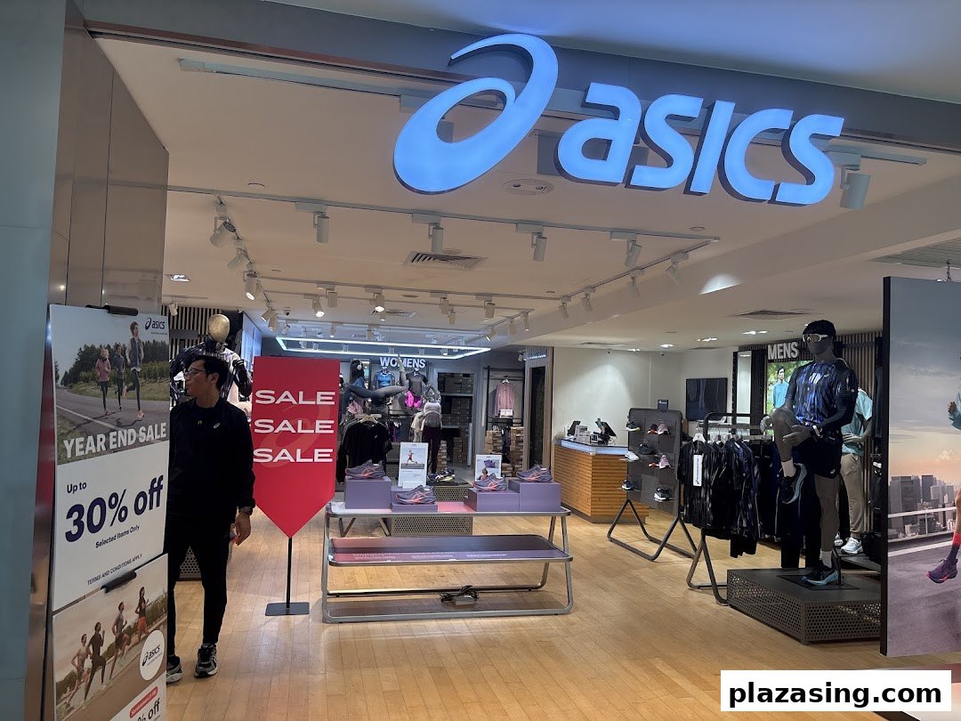 The ASICS store entrance features its prominent logo, sale signage, and athletic apparel displays.