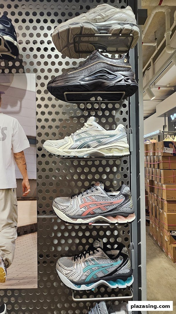 A display of various ASICS sneakers on a perforated wall rack inside the store.