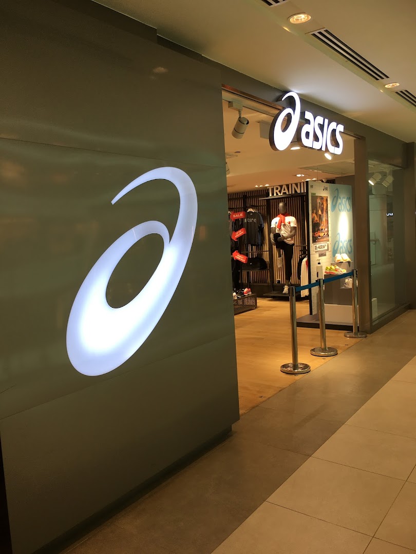 The brightly lit ASICS store entrance showcasing its iconic logo and athletic apparel inside.