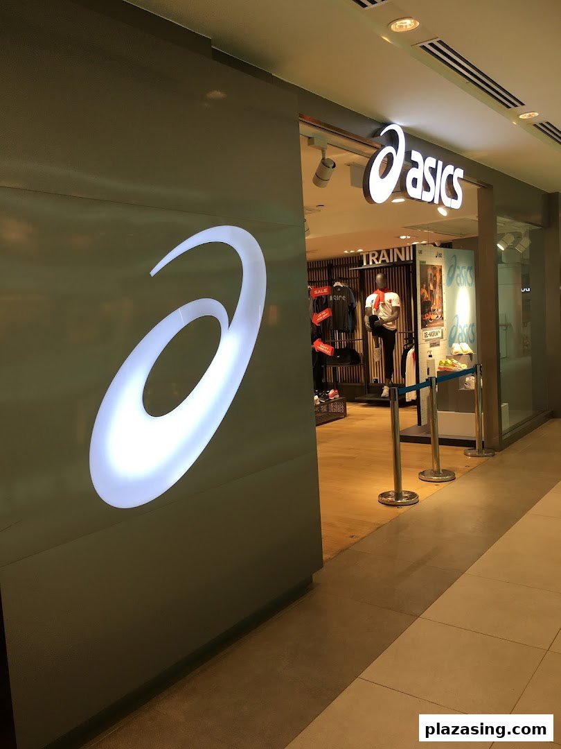 The brightly lit ASICS store entrance showcasing its iconic logo and athletic apparel inside.