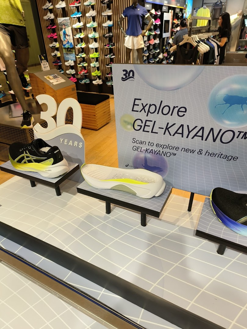 ASICS shop interior featuring a prominent GEL-KAYANO shoe display and promotional signage.