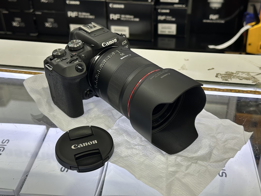 A Canon EOS R10 camera with an RF 35mm lens displayed in a photo electronics shop.