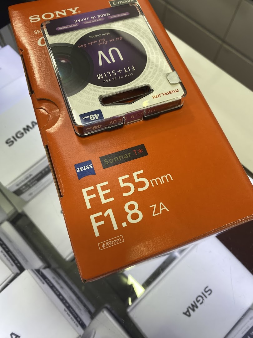 A Sony FE 55mm F1.8 ZA lens box with a Marumi UV filter package on top.