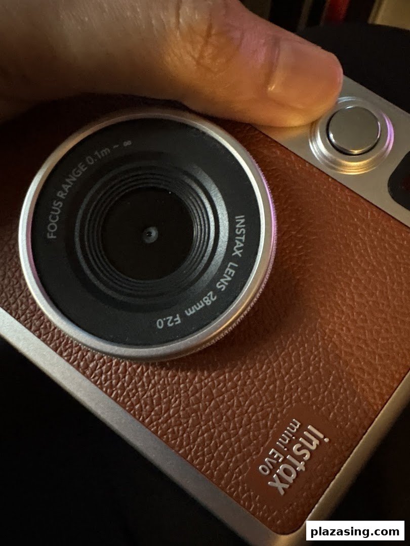 Close-up of a hand holding a stylish brown Instax Mini Evo instant camera.