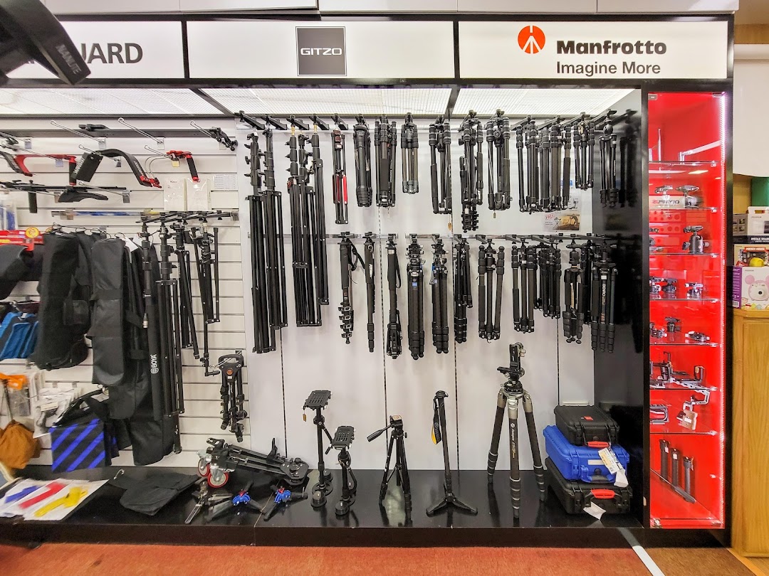 A retail display showcasing a wide selection of camera tripods and photography accessories.