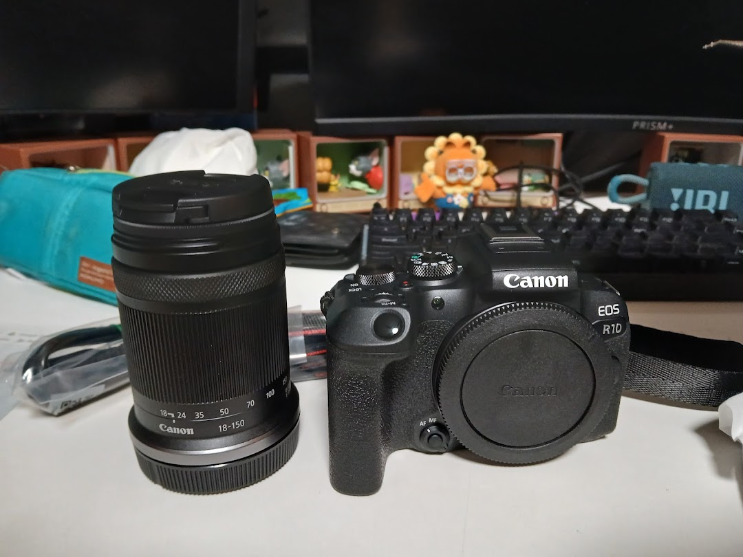 A new Canon EOS R10 camera body and an 18-150mm lens displayed on a desk.