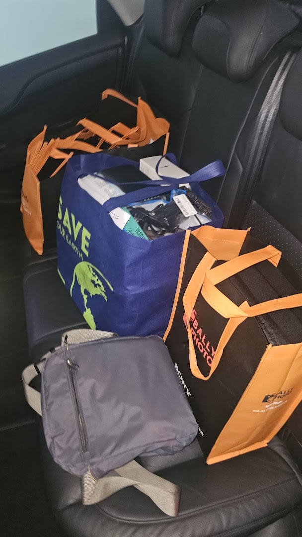 Shopping bags, including one from Bally Photo Electronics, filled with purchases in a car.