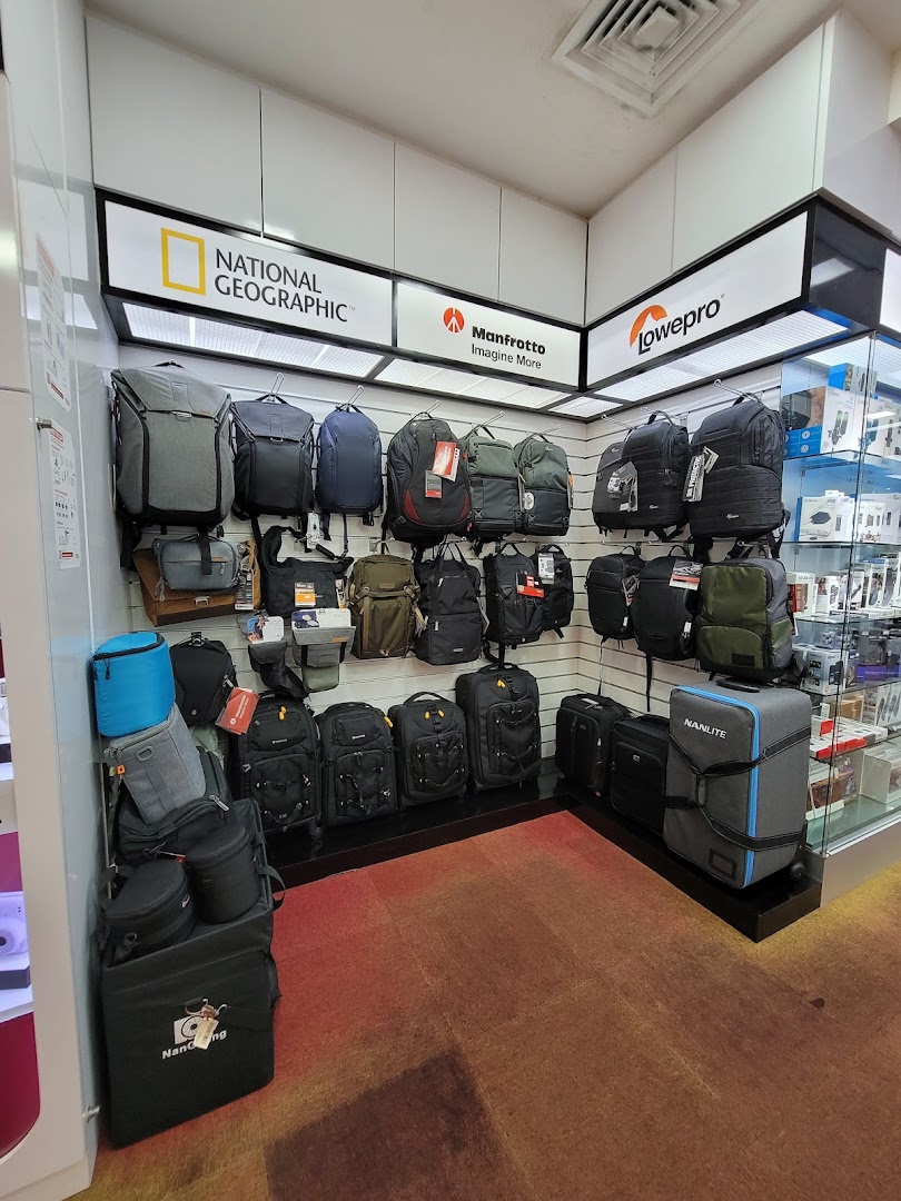 A retail display showcasing various camera bags and backpacks from top brands like National Geographic and Manfrotto.